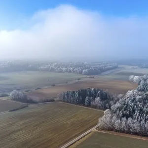 Aerial view of a winter landscape covered in clouds of fog
