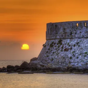 Agios Nikolaos fortress, sunrise behind an old castle wall with gentle sea waves