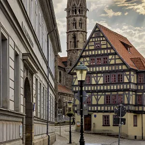 Alley with a view of a half-timbered house and a church tower Alley with a view of a half-timbered house and a church tower
