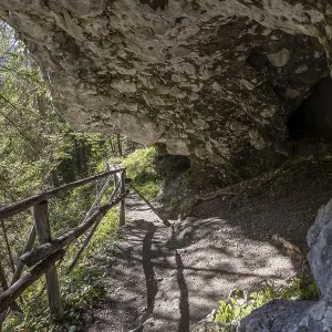 Alpine hiking trail on the rock with grotto cave