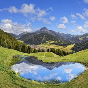 Alpine meadow with small lake and reflection