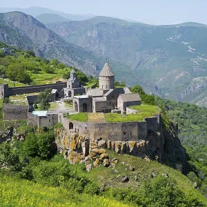 An ancient monastery sits majestically on a hill overlooking a mountainous landscape An ancient monastery sits majestically on a hill overlooking a mountainous landscape