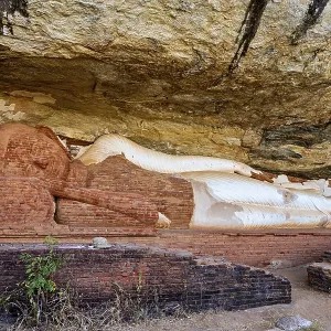 Ancient sandstone sculpture of a Buddha reclining under a rocky outcrop Ancient sandstone sculpture of a Buddha reclining under a rocky outcrop