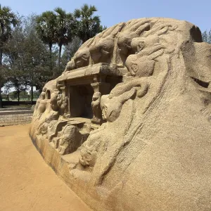Statue de pierre ancienne avec des reliefs sous un ciel bleu ensoleillé.