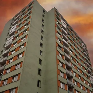 Apartment building with a green facade stands against a dramatic orange sunset sky