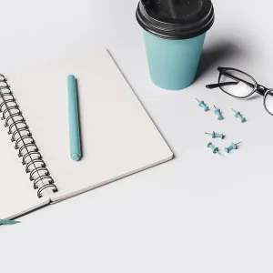 Artificial fern leaves pen white blank spiral notebook with coffee cup eyeglasses push pin Artificial fern leaves pen white blank spiral notebook with coffee cup eyeglasses push pin