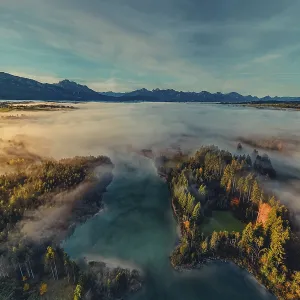 Autumn sunrise in the foothills of the Alps with fog at Illasbergsee and Forggensee near Halblech in Allgau