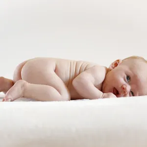 Baby girl, 3 months old, lying on a sheepskin
