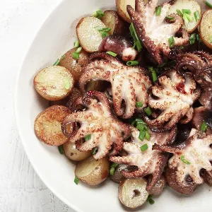 Baby grilled octopus with golden baked potatoes and fresh herbs