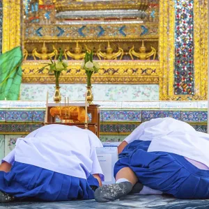 Bangkok, Thailand - Sep 11, 2015: School kids praying and singing at Wat Phra Kaew emerald buddha temple