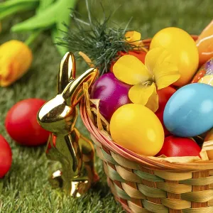 A basket with colorful eggs, flowers and Easter decoration in a meadow