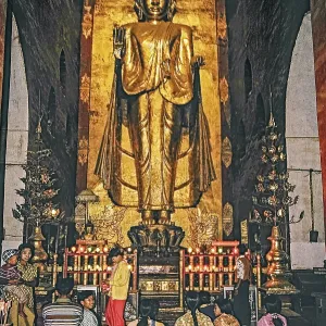 Believers standing in front of a large Buddha in Ananda Temple in Bagan