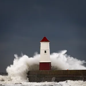 Berwick Lighthouse with strong surf and dark cloudy sky