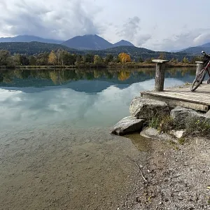 A bicycle is leaning on a footbridge over a still lake