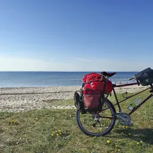 Bicycle with luggage in front of a lonely sandy beach with jetty Bicycle with luggage in front of a lonely sandy beach with jetty
