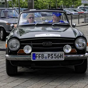 Black cabriolet classic car with two people in front view during a car event