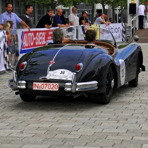 Black classic car from behind with audience and atmosphere of the event