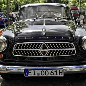 The front of a black classic car with distinctive radiator grille stands on a street The front of a black classic car with distinctive radiator grille stands on a street