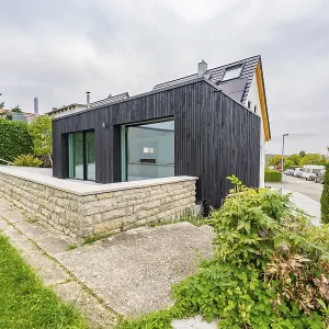 Black, modernly clad extension with large glass areas on lawn Black, modernly clad extension with large glass areas on lawn