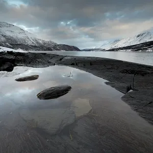 Black rocky coast in a bay in the Ullsfjord Black rocky coast in a bay in the Ullsfjord