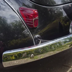 Black vintage car with chrome-plated bumper and illuminated tail light