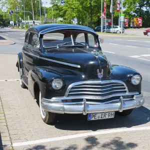 A black vintage car is parked in a car park on a road A black vintage car is parked in a car park on a road