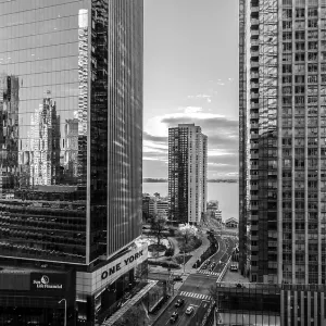Black and white view of skyscrapers with reflective surfaces and cloudy sky in Toronto