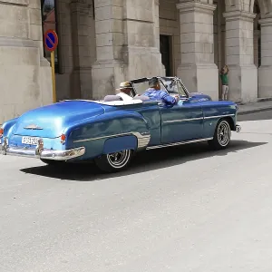 Blue convertible drives past a historic building Blue convertible drives past a historic building