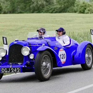 Blue racing gold car with two occupants on a country road