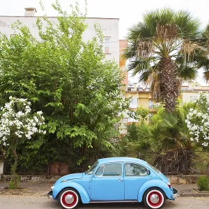 A blue Volkswagen Beetle is parked in a beautiful location A blue Volkswagen Beetle is parked in a beautiful location