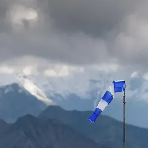 Blue and white windsock on the summit of the Nebelhorn in front of the mountain range with dark clouds Blue and white windsock on the summit of the Nebelhorn in front of the mountain range with dark clouds