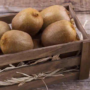 Box of fresh kiwi in on wooden background Box of fresh kiwi in on wooden background