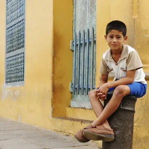 Boy sitting on a cannon, bollard in the historic centre of Trinidad Boy sitting on a cannon, bollard in the historic centre of Trinidad