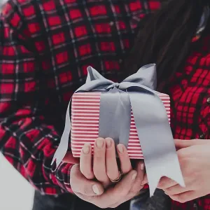 Boyfriend giving a gift box present with ribbon outdoor due to Saint Valentine day to her girlfriend Boyfriend giving a gift box present with ribbon outdoor due to Saint Valentine day to her girlfriend