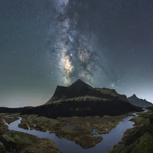 Ciel nocturne époustouflant sur l'Islande, capturant la Voie lactée au-dessus d'une rivière paisible et de montagnes escarpées.
