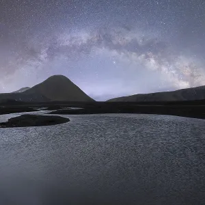 Vue imprenable de la Voie lactée s'arcant sur un paysage islandais paisible
