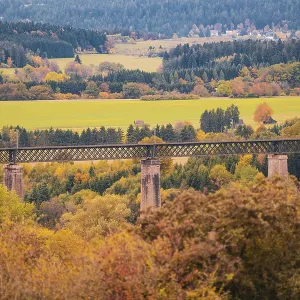 Bridge over an autumn landscape with colorful trees and meadows