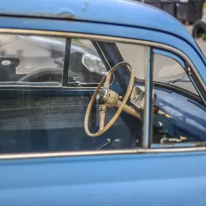 Side part of bright blue old automobile with wheel in window