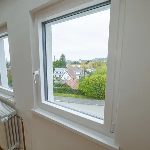 Bright room with white windows and views of residential buildings and greenery Bright room with white windows and views of residential buildings and greenery