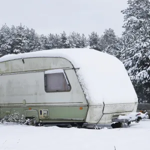Broken tourist car trailer covered with snow in the winter forest landscape