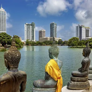 Bronze Buddha statues with yellow cloths look at the skyline of a city Bronze Buddha statues with yellow cloths look at the skyline of a city