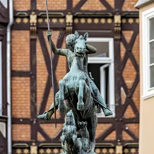 Bronze equestrian statue in front of half-timbered houses in urban surroundings Bronze equestrian statue in front of half-timbered houses in urban surroundings