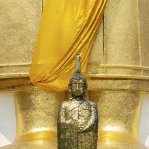 Buddha figure decorated with gold leaf in front of a 32 metre high standing Buddha statue Buddha figure decorated with gold leaf in front of a 32 metre high standing Buddha statue