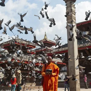 Buddhist monk with a begging bowl standing in front of Hindu temples Buddhist monk with a begging bowl standing in front of Hindu temples