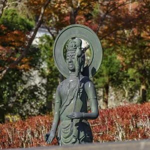 Buddhist statue in front of autumn trees