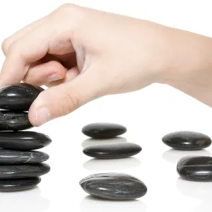 Building a Zen garden. hand and stones on white background Building a Zen garden. hand and stones on white background