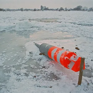 Buoy lying on ice rink, frozen Elbe