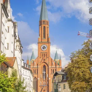 A busy urban centre is dominated by a tall church tower