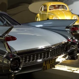 Cadillac with fins and yellow VW Beetle in the background in an exhibition