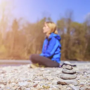 Cairn on a pebble beach, meditating woman in the background Cairn on a pebble beach, meditating woman in the background